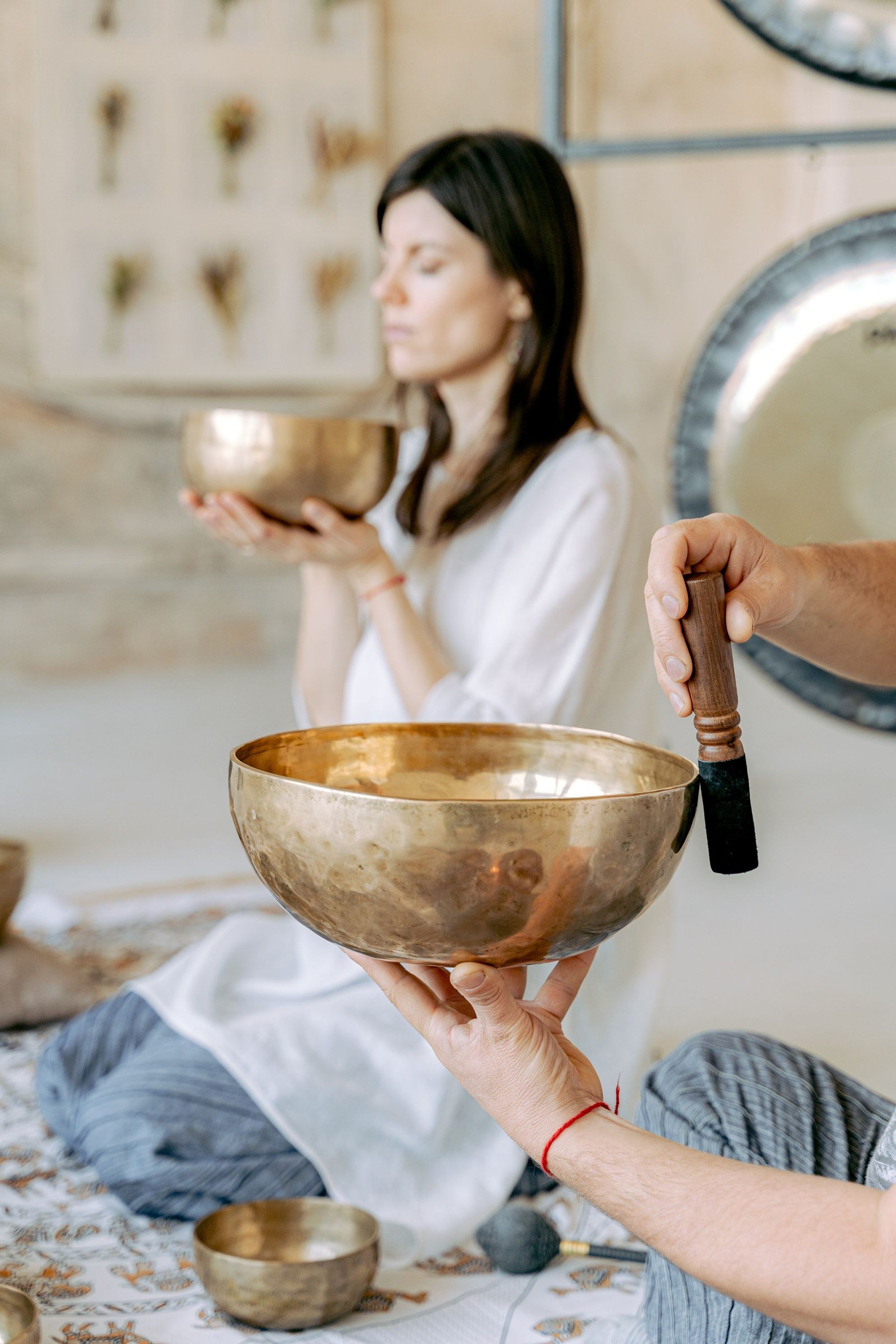 A sound practitioner and a guest sharing brass singing bowls during a session
