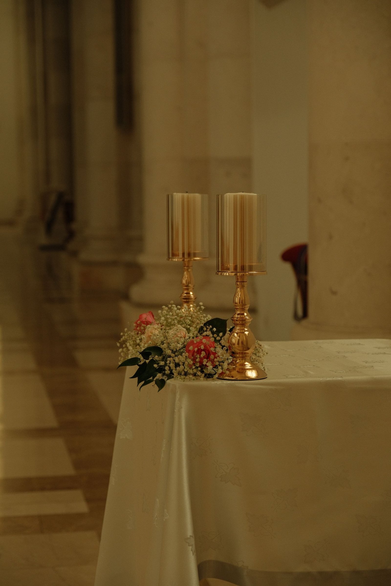 Golden candle holders and a small floral arrangement on a linen table