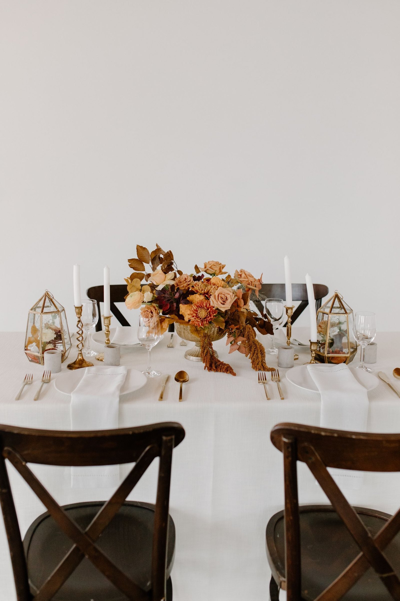 A styled table with an autumn floral centrepiece and gold candle holders