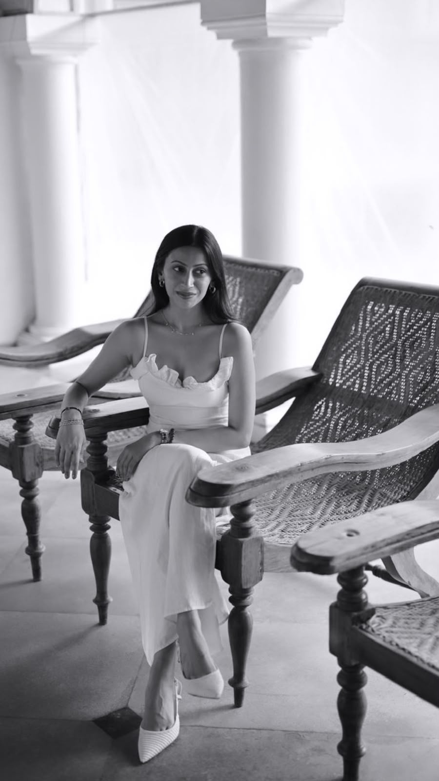 Sanjana, founder of Athena Experiences, seated on a planter's chair in a white dress