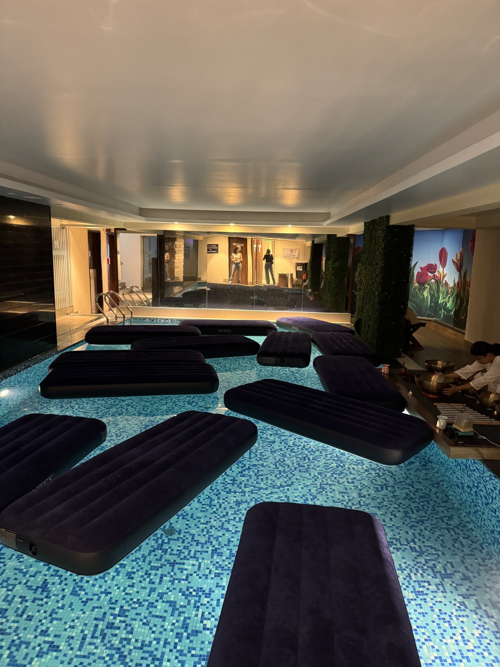 An indoor pool set with floating beds for a private sound bath